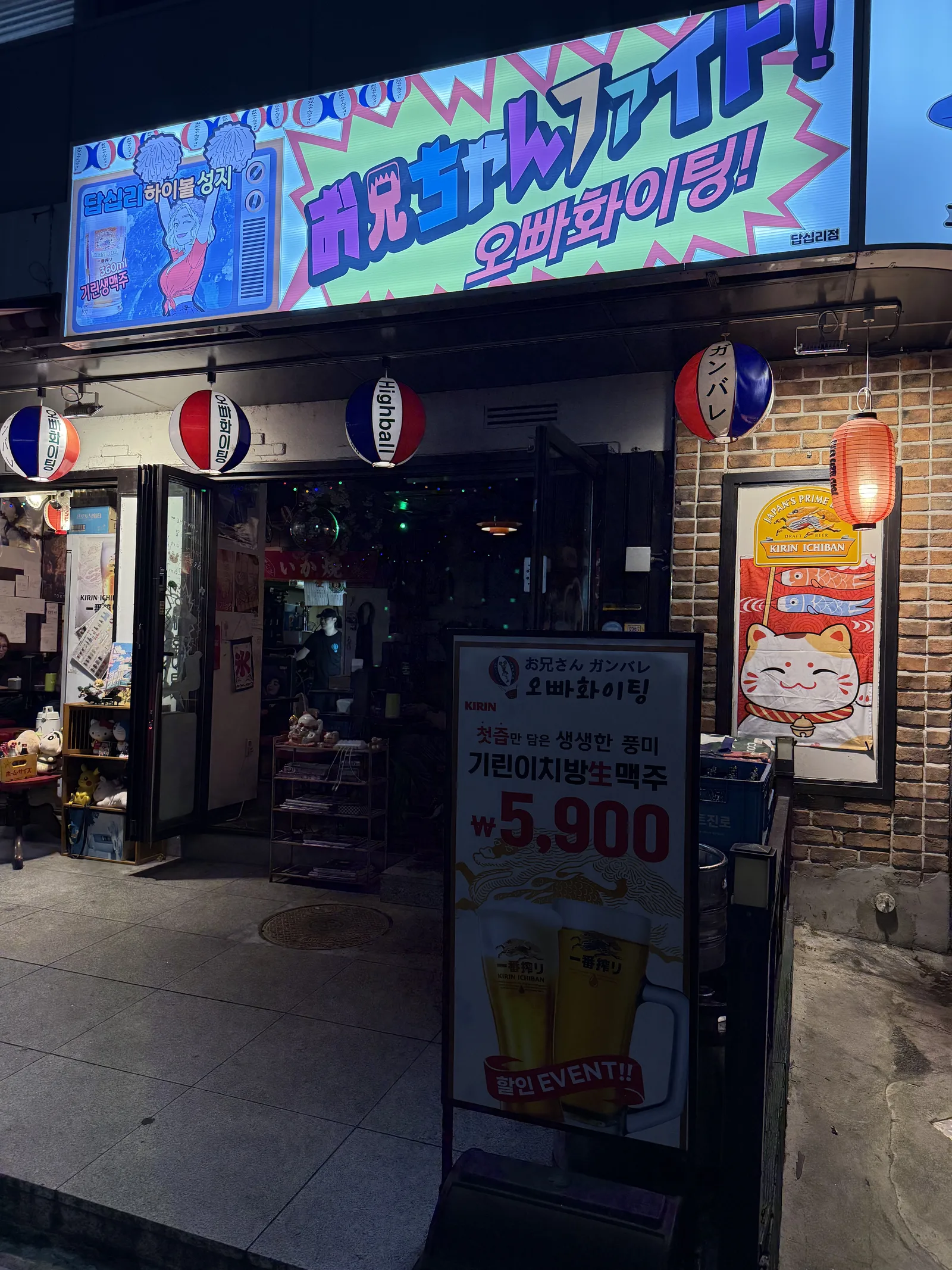 밤에 불 켜진 일본식 이자카야 입구와 기린 생맥주 가격 입간판
