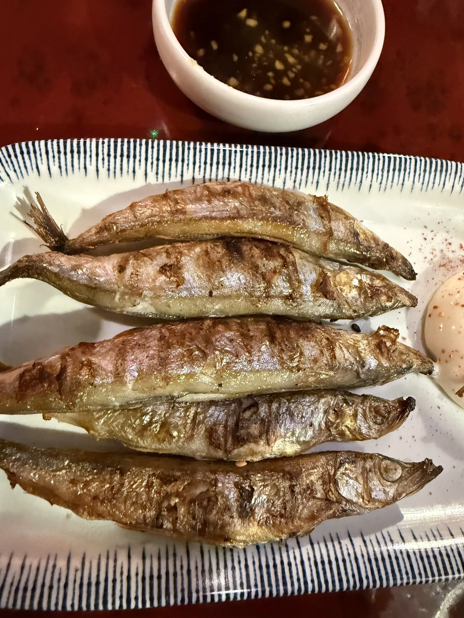 빗살무늬 접시에 담긴 구운 생선 다섯 마리와 간장 소스
