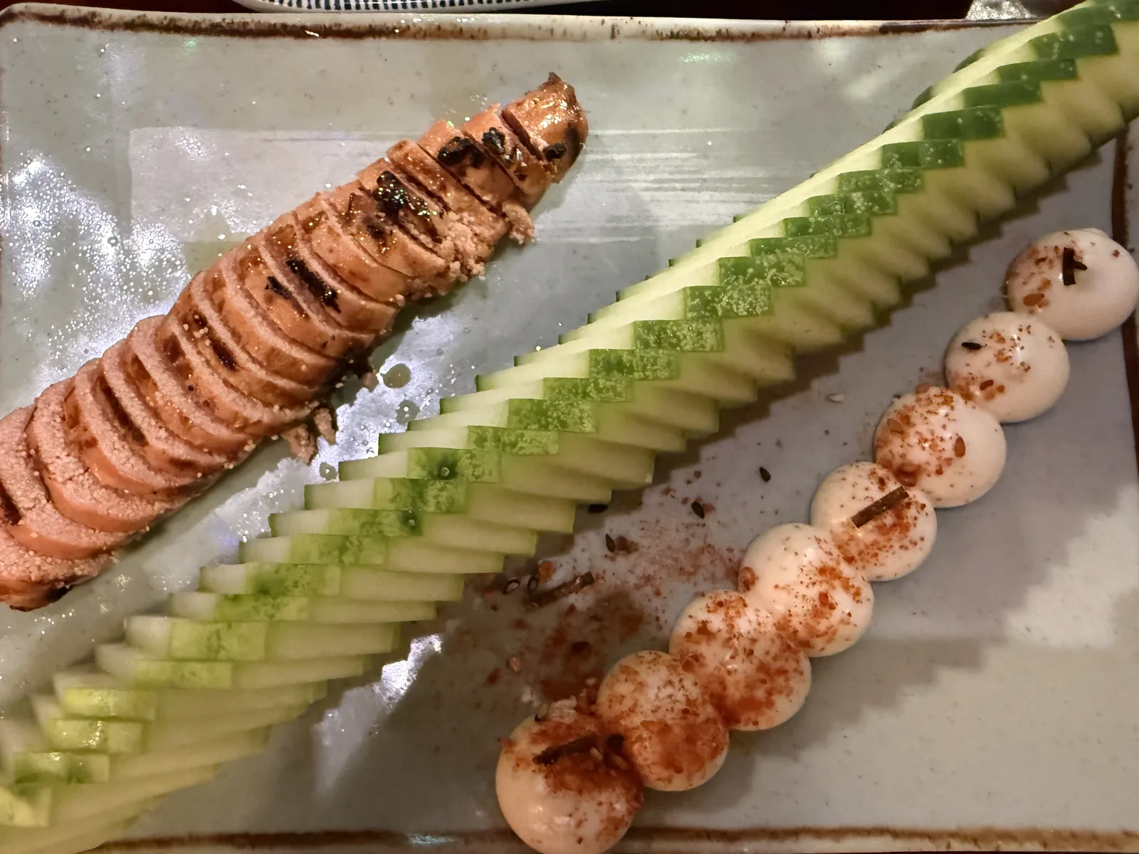 토치로 구운 연어 슬라이스와 톱니 오이, 마요네즈가 담긴 사각 접시