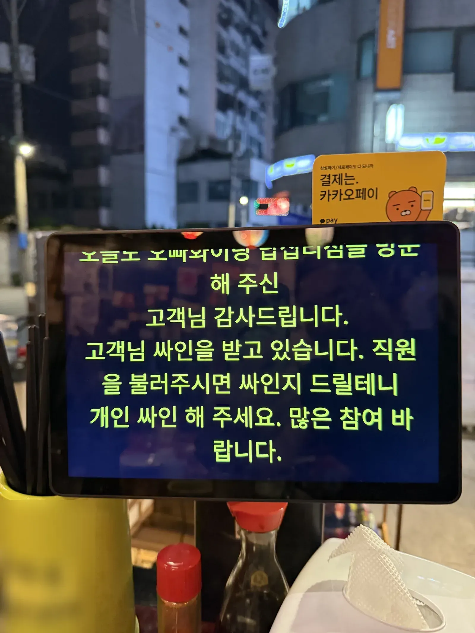 식당 테이블의 태블릿 안내 화면과 젓가락통, 양념통