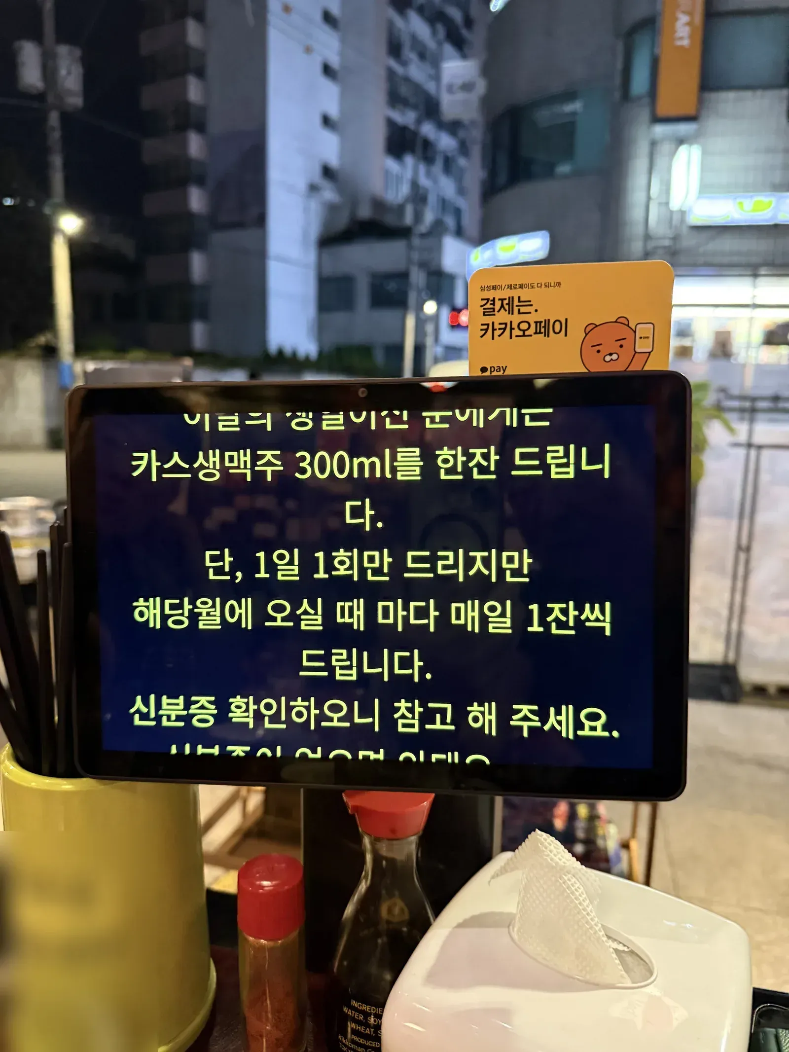 생맥주 증정 안내가 뜬 태블릿과 테이블 위 양념통들