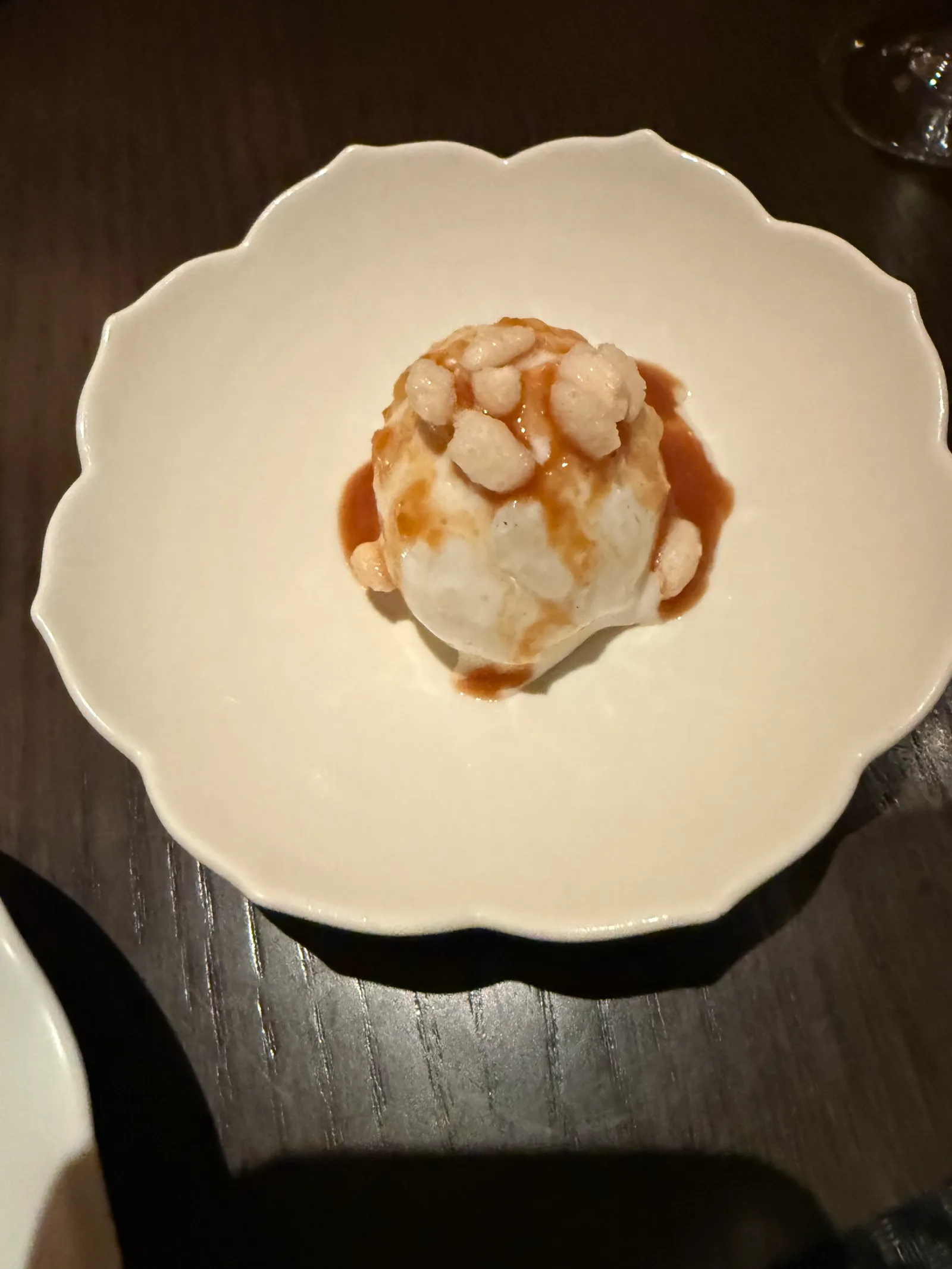 갈색 소스와 퍼프가 올려진 아이스크림이 담긴 꽃 모양 흰 접시