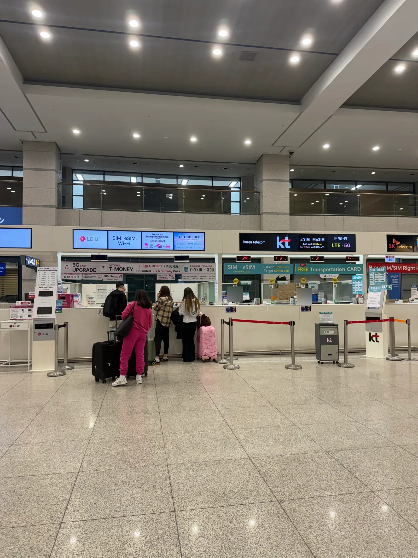 Telecom SIM and eSIM counters in the arrivals hall with signs advertising free or preloaded T-money cards