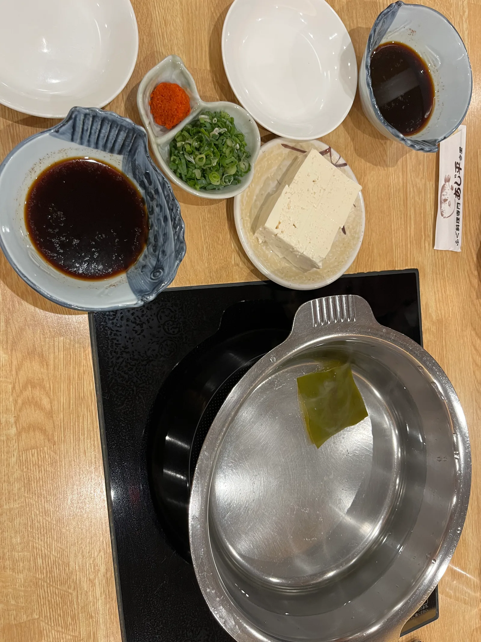 다시마를 넣은 냄비와 폰즈 종지, 두부, 쪽파가 차려진 나베 상차림