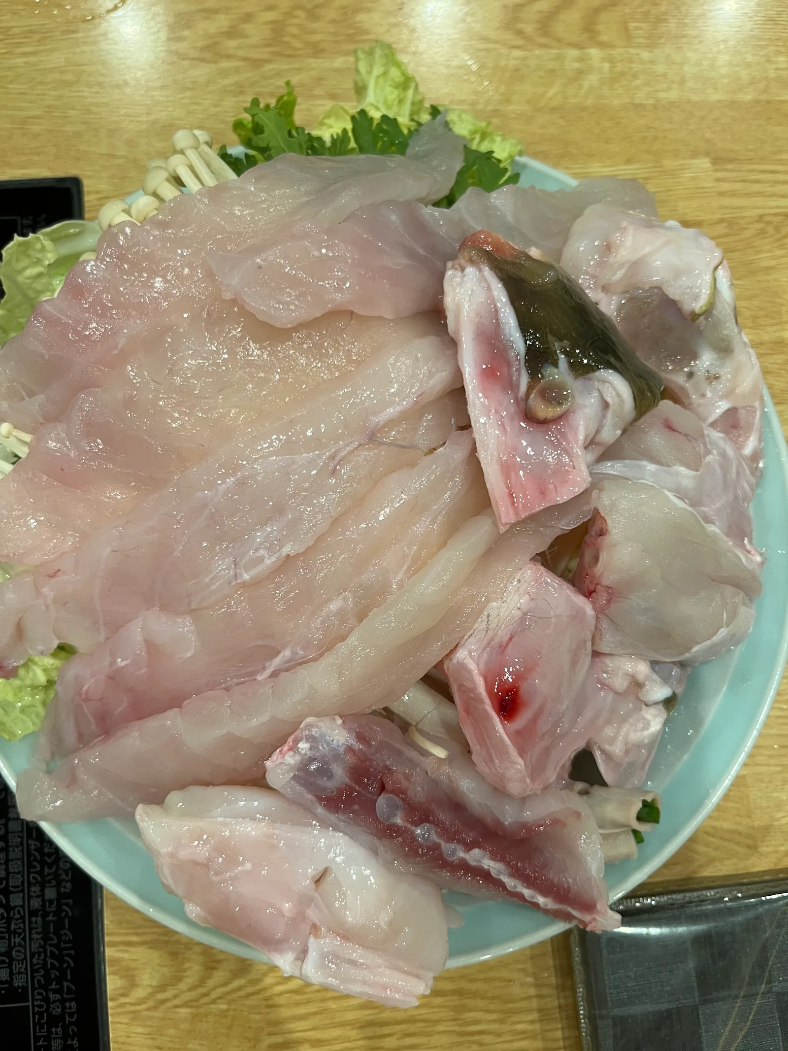 접시에 담긴 생선 살과 머리 토막, 팽이버섯과 채소
